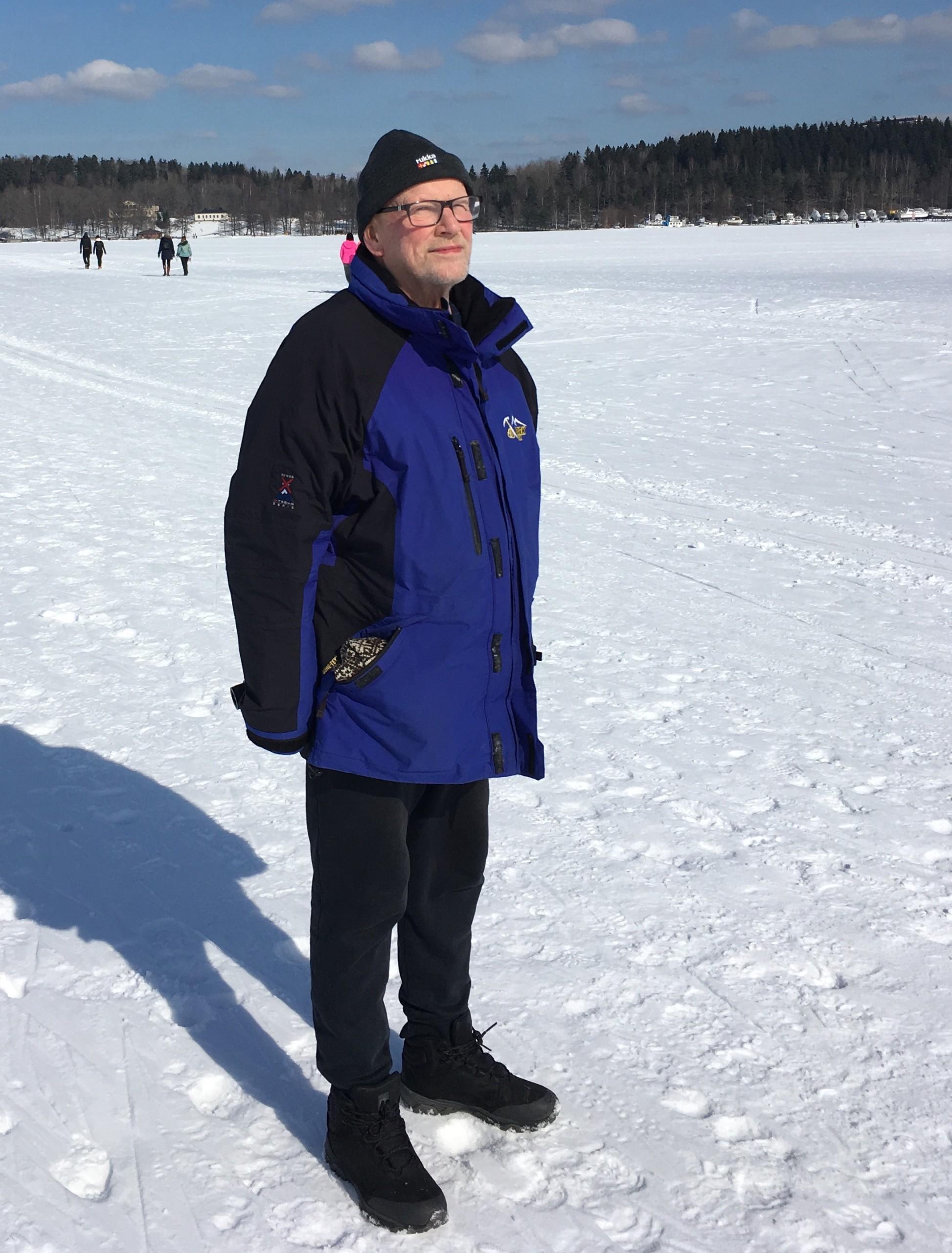 Matti Leppäranta seisoo jäätyneen järven jäällä. Jää on lumen peitossa.