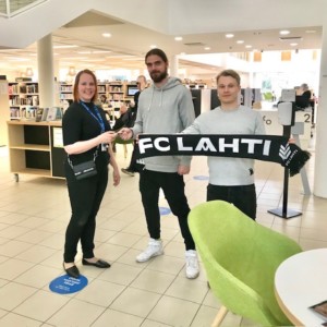 Kirjastopalvelujohtaja Salla Palmi-Felin vastaanottaa kausikortin FC Lahden pelaajalta. Kuva vuodelta 2022.